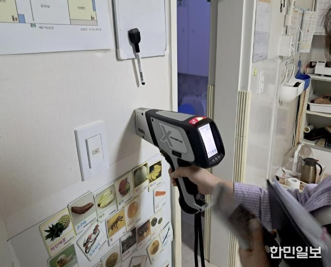 구청 관계자가 어린이집 실내 벽에 사용된 도료의 중금속 함량을 측정하고 있다