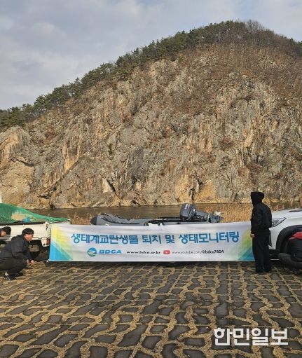 금산군 생태계 교란어종 퇴치 사업 관계자들이 활동에 나서며 현수막을 설치하고 있다.