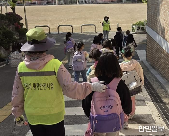 초등학교 학생들이 워킹스쿨버스 안전지도사와 함께 등교하고 있다.