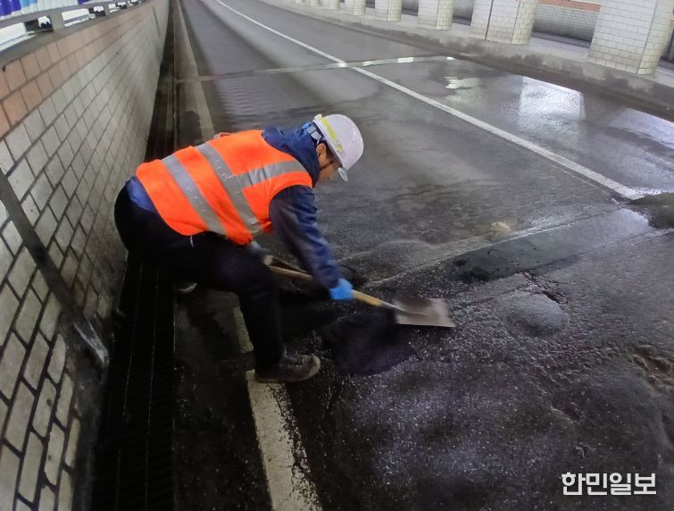 천안시 도로보수원들이 겨울철 폭설과 염화칼슘 영향으로 훼손된 도로 포트홀 구간에 아스콘을 충진하며 긴급 복구 작업을 진행하고 있다
